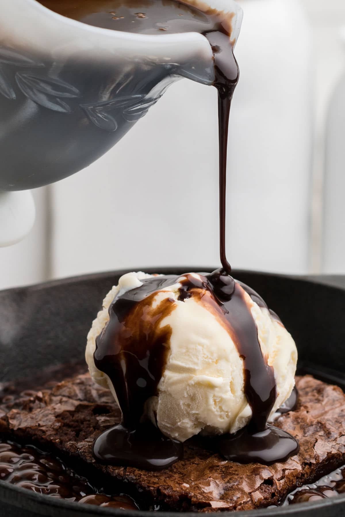 a close up of some chocolate sauce being poured over icecream on a brownie in a hot skillet