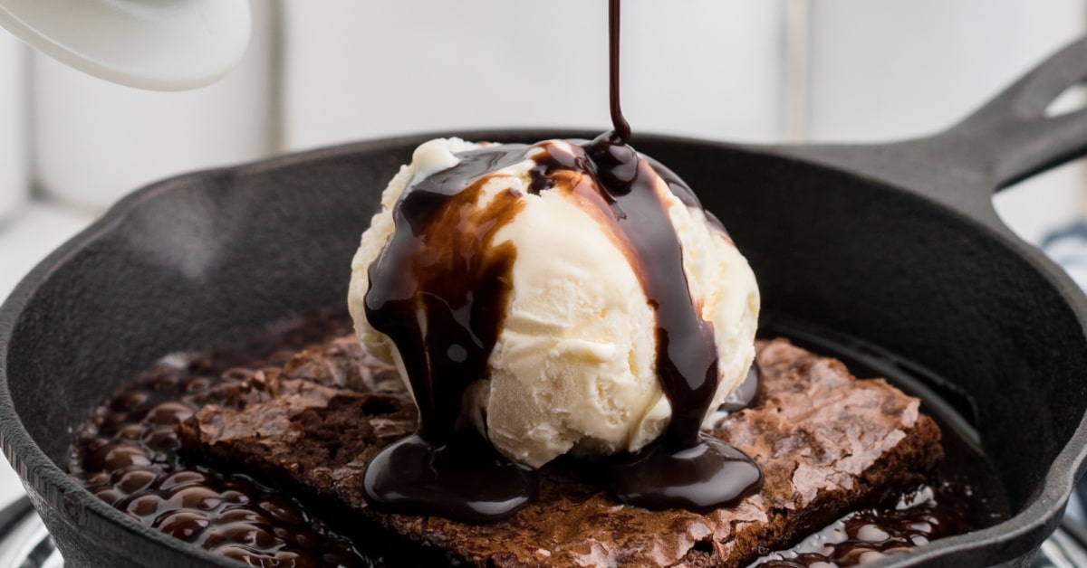 a close up of some chocolate sauce being poured over icecream on a brownie in a hot skillet