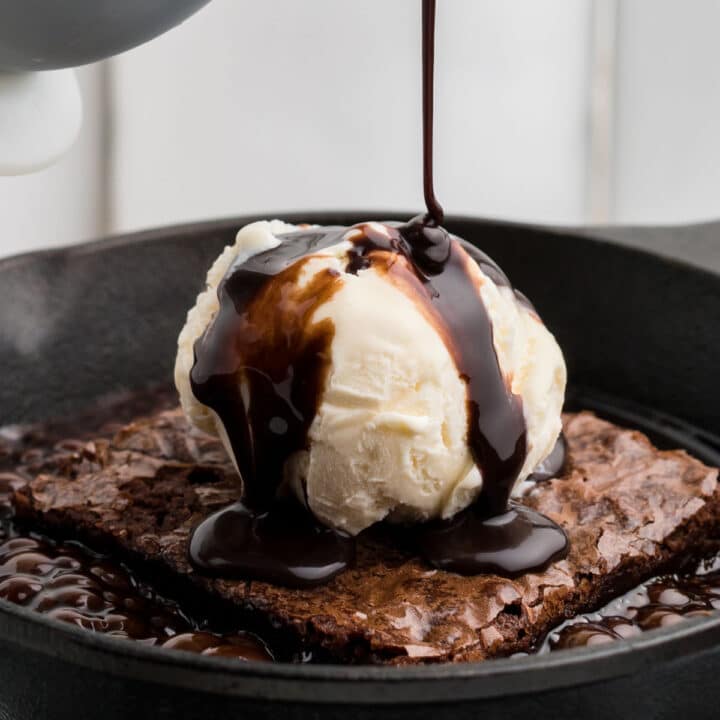 a close up of some chocolate sauce being poured over icecream on a brownie in a hot skillet