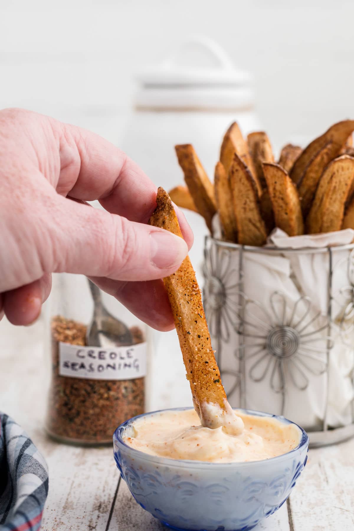 a cajun fry being dipped in some mayonnaise looking dip