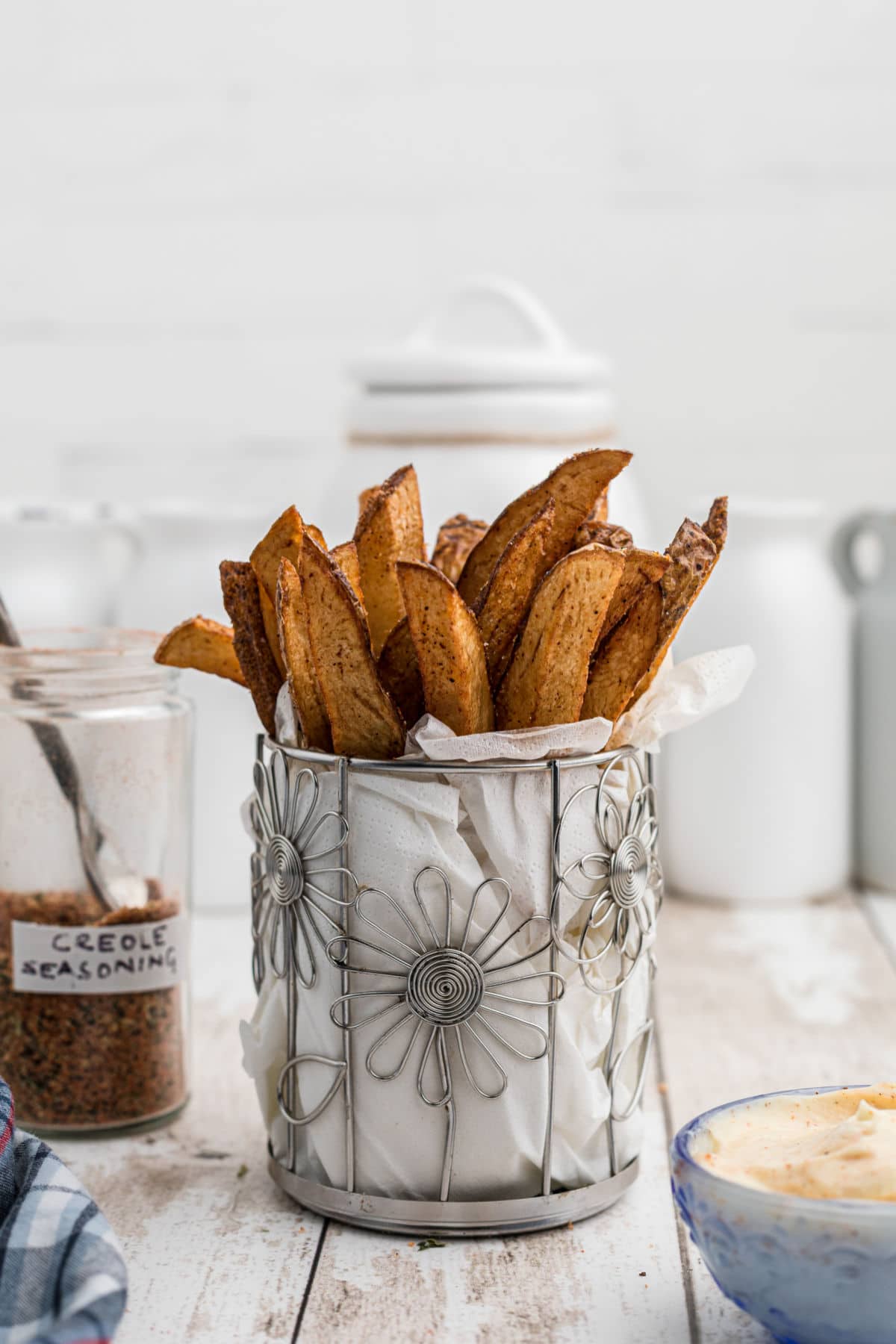 a closeup image of some popeyes cajun fries in a cylindrical flower like container with white paper towel