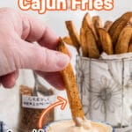 a cajun fry being dipped in some mayonnaise looking dip