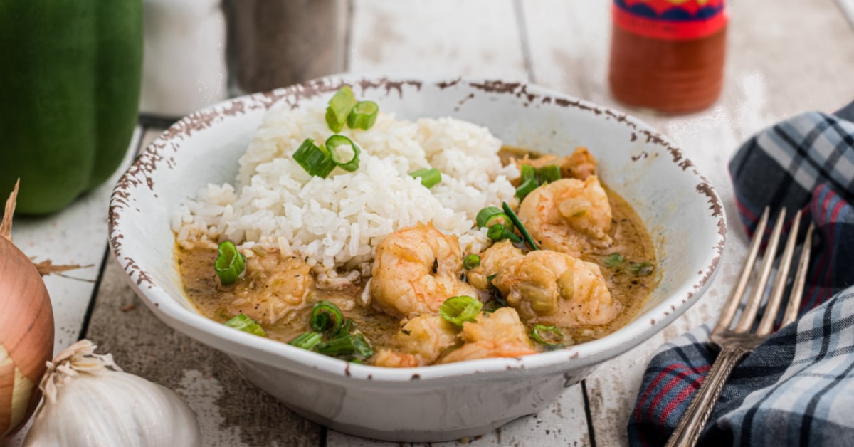 a bowl of shrimp etouffee with rice piled in there, topped with chopped green onions