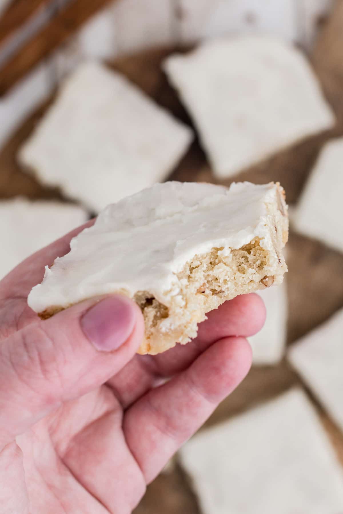 a close up of a hand holding a vanilla brownie with a bite taken out of it