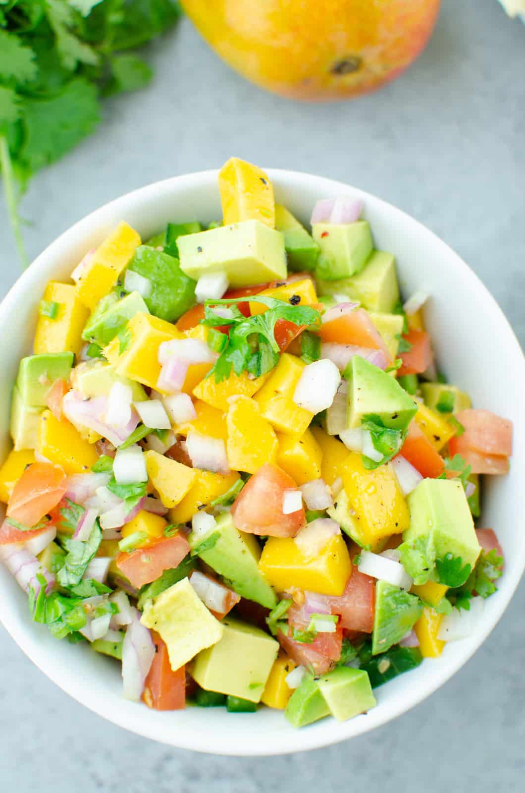 a bowl full of mango avocado and other salad items