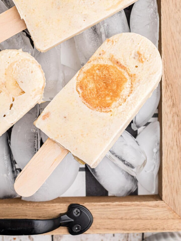 close up of a tray with ice on it and banana pudding popsicles laying on top of the ice