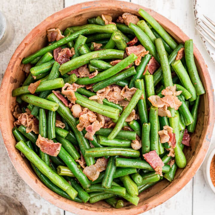 close up of a ceramic bowl full of cajun green beans with bacon