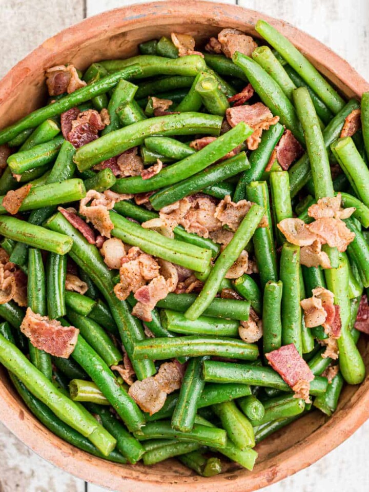 close up of a ceramic bowl full of cajun green beans with bacon