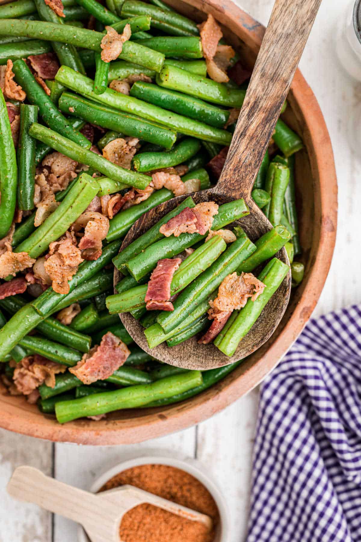 a close up of a bowl of cajun green beans with a serving spoon digging in