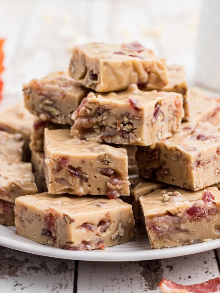a plate full of maple bacon fudge with a maple leaf in the background and some bacon slices