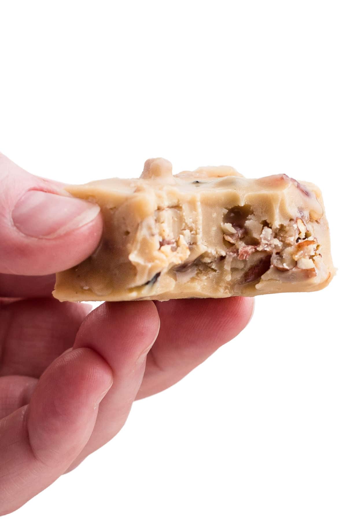 a hand holding a piece of maple bacon fudge with a bite taken out