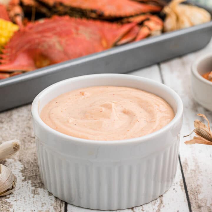 A bowl of seafood sauce with some boiled crabs in the background