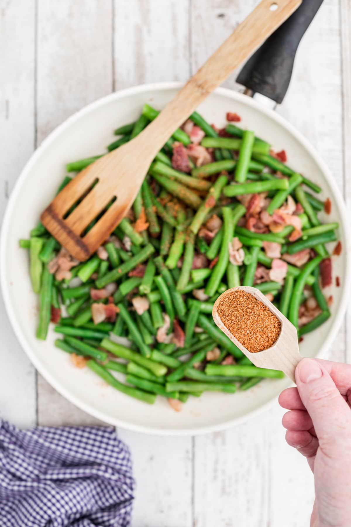 seasoning being added to some green beans and bacon
