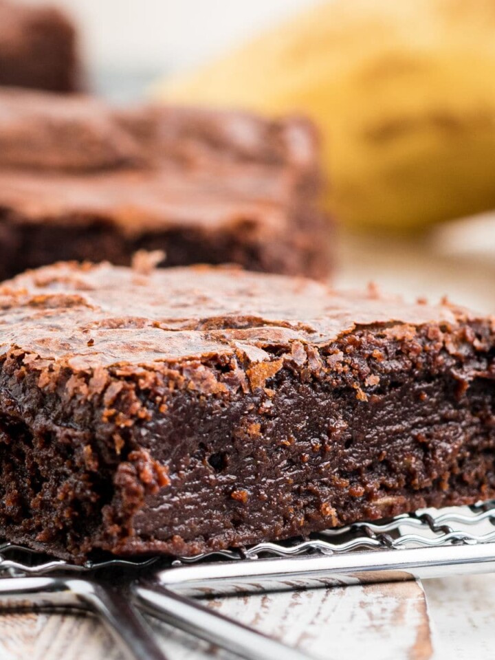 a close up of a moist banana brownie with a banana in the background