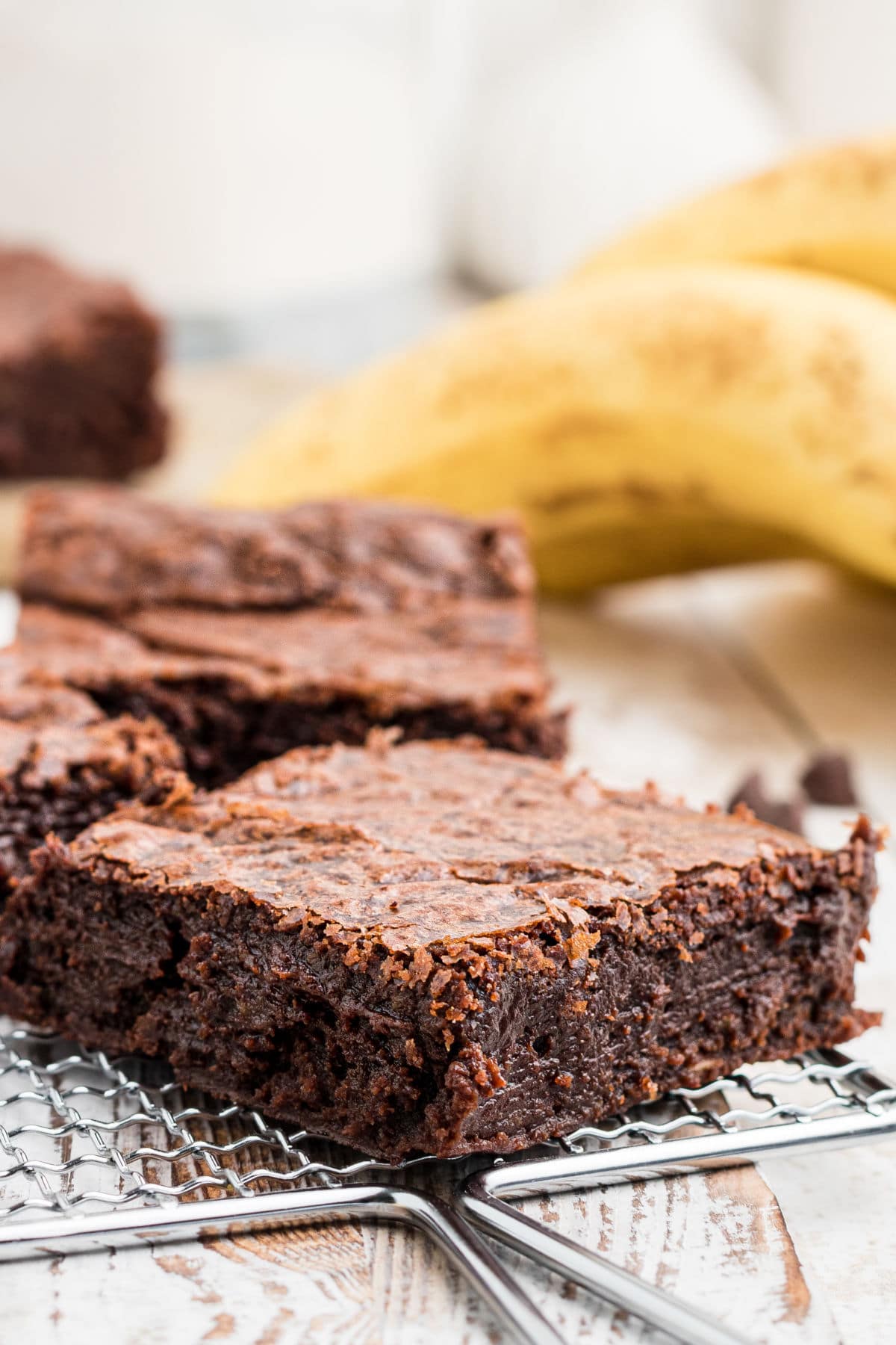 a close up of a banana brownie with bananas in the background