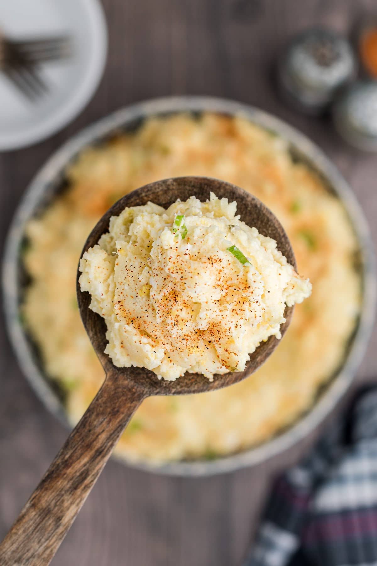 A wooden spoon with some potato salad on it.