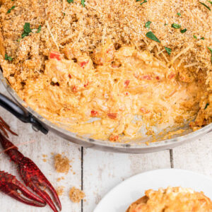 skillet of crawfish dip with breadcrumbs on top, with cream cheese. Crawfish in the corners.