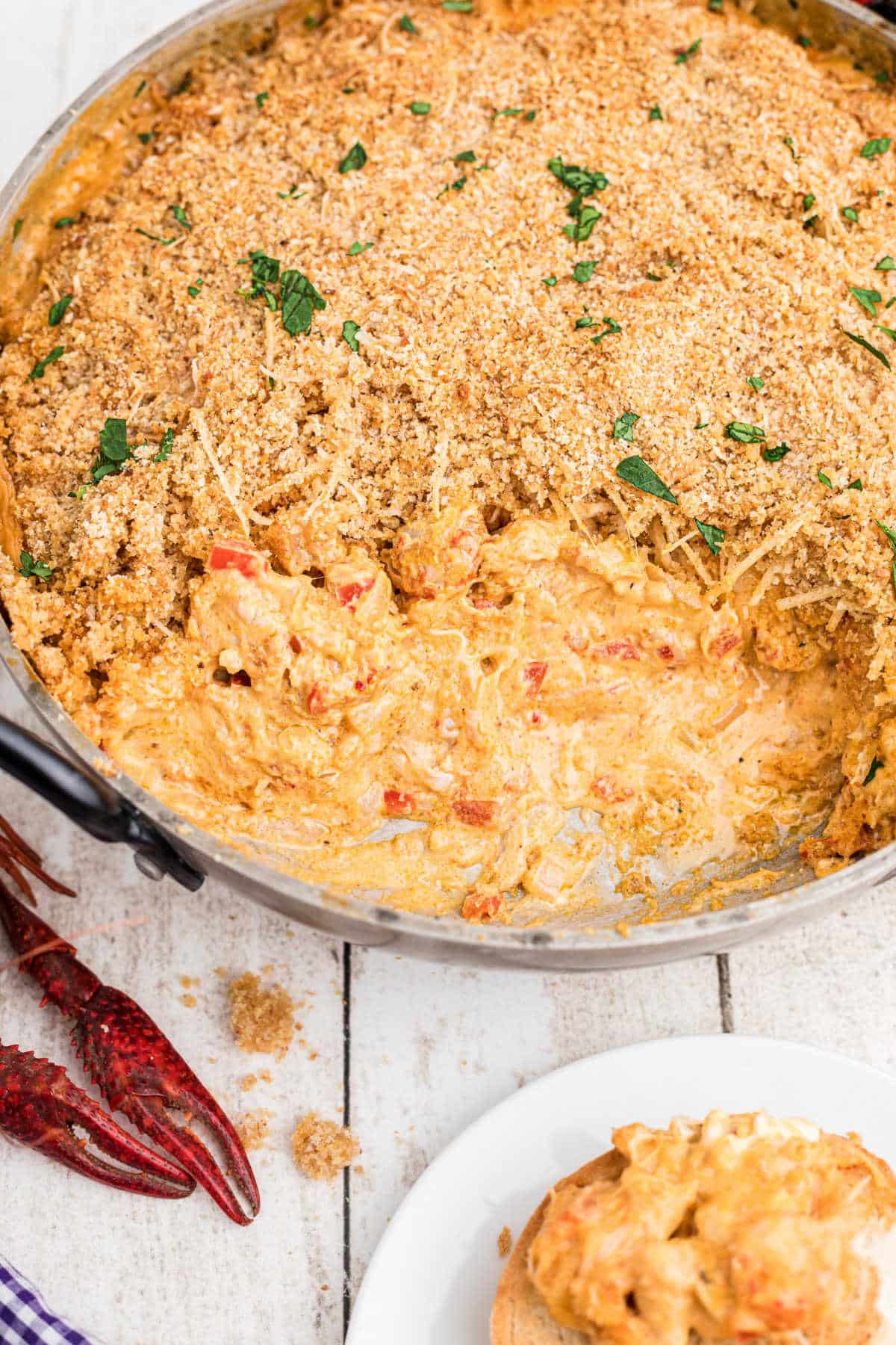 large skillet full of crawfish dip with breadcrumbs on the top, a very cheesy dip. with boiled crawfish in the corners.