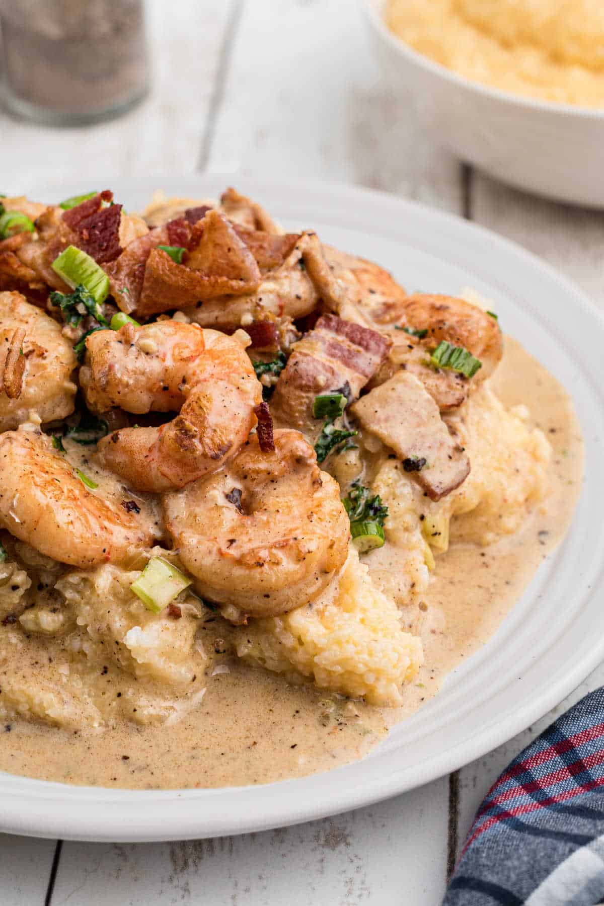 Side shot of a plate of creole shrimp and grits, up close.