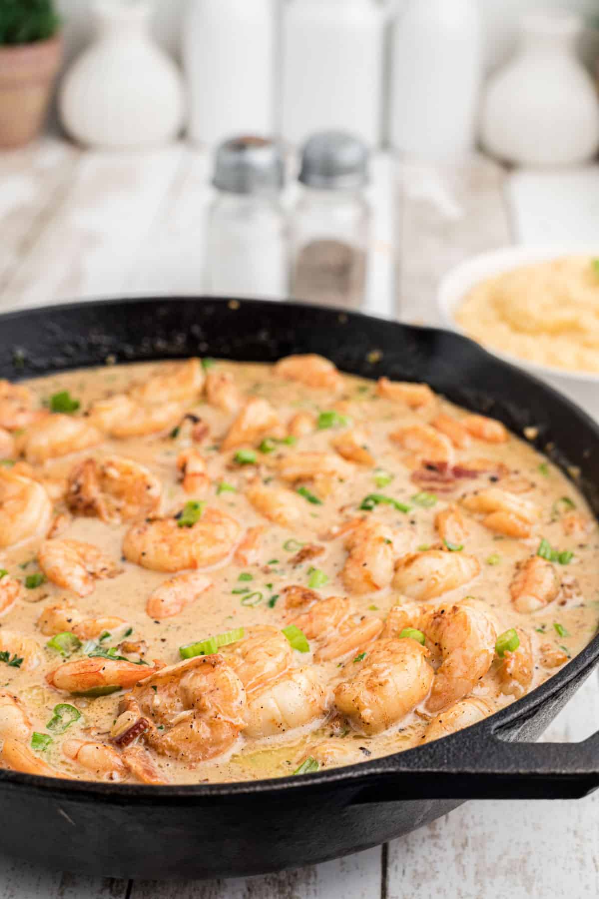 Side shot of a skillet of Creole shrimp in cream sauce.