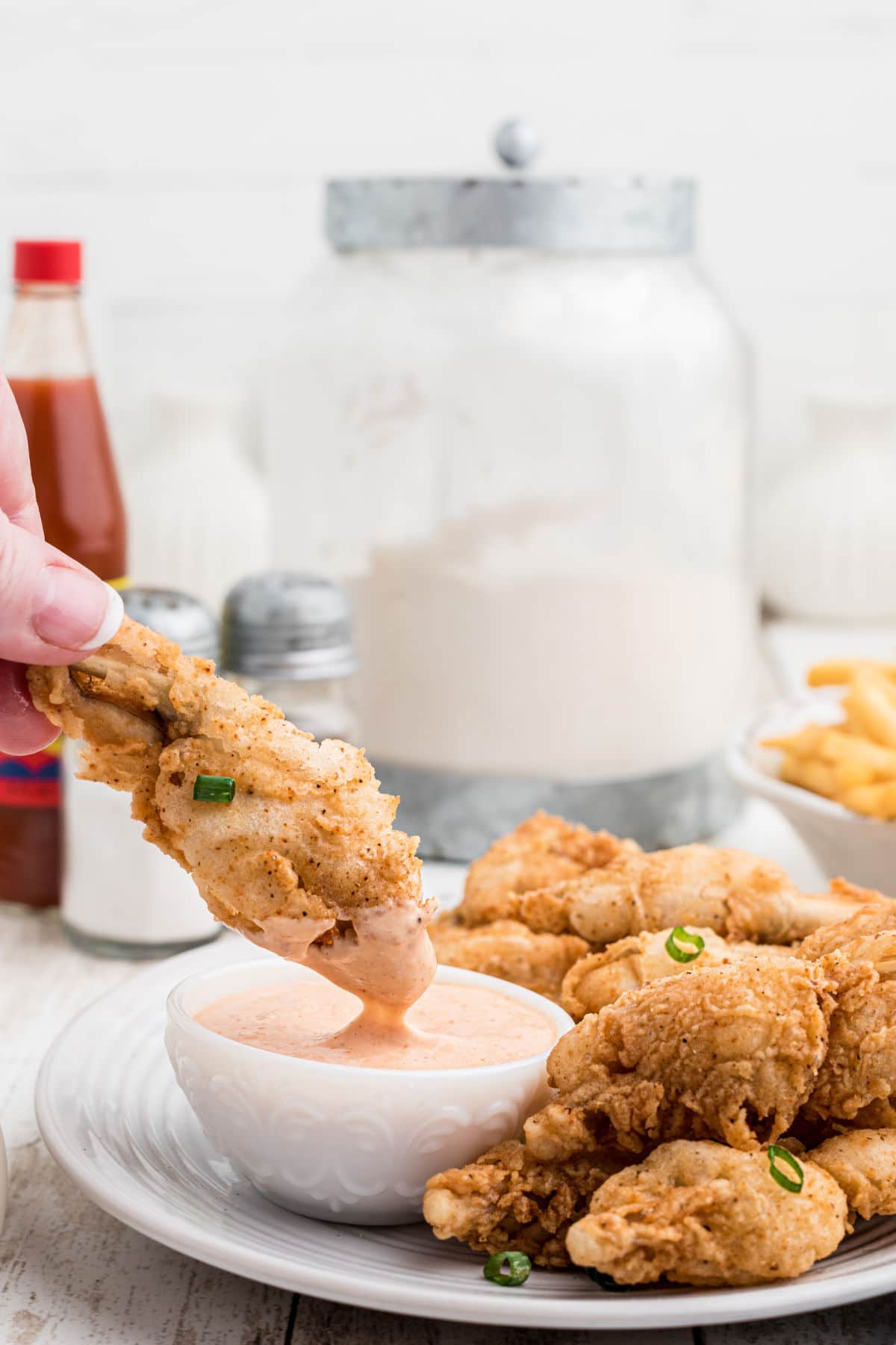 a fried frog leg being dipped into a bowl of dip