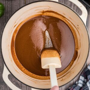 a spoon stirring a dark roux