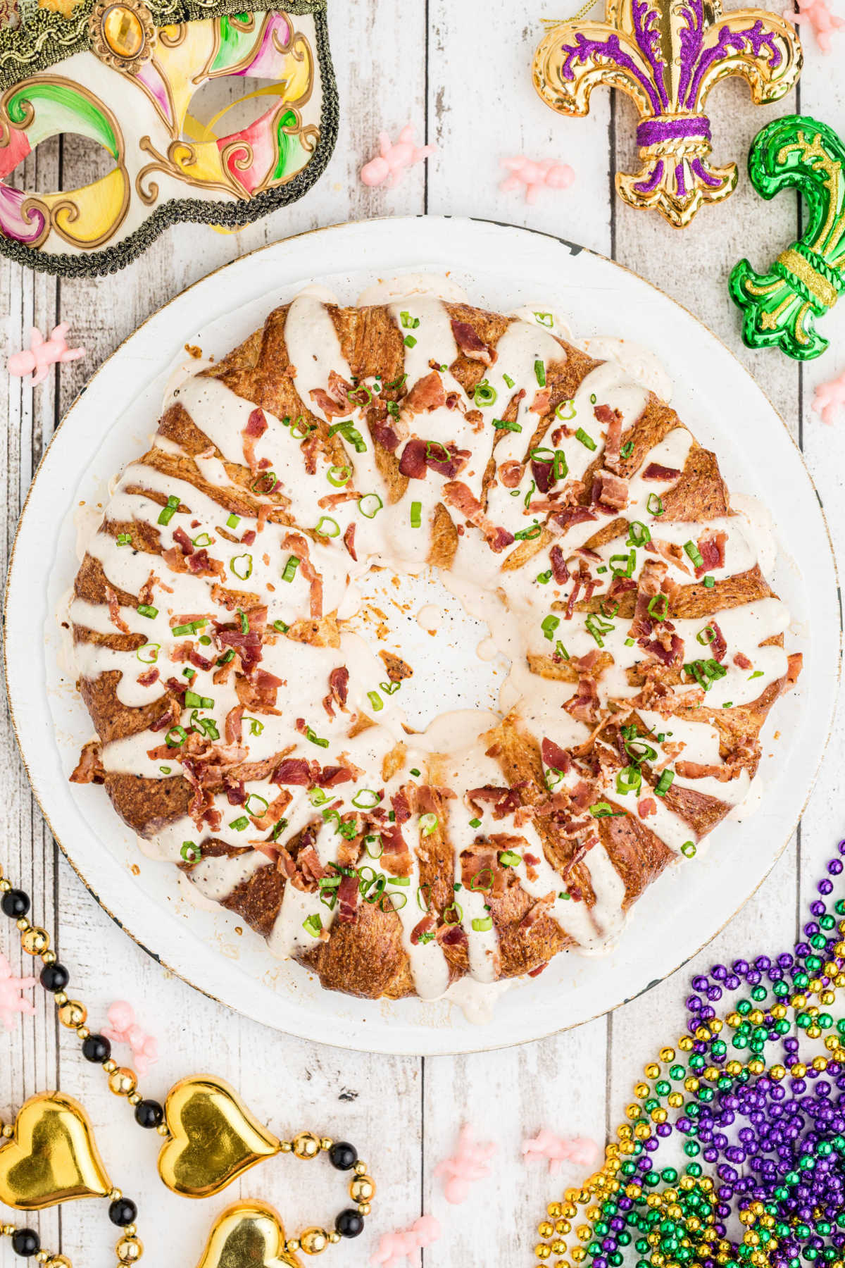 overhead view of a boudin king cake with some mardi gras stuff scattered around