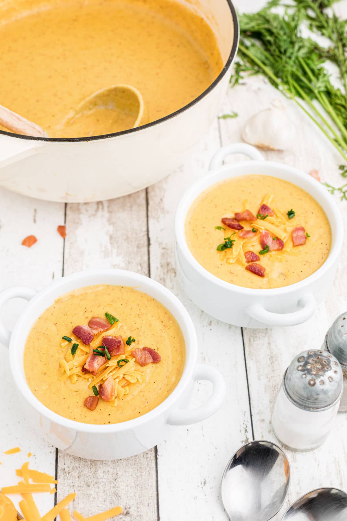 a side view of two bowls of baked potato soup with the pot in the background