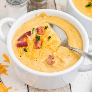picture of a bowl of saltgrass baked potato soup with bacon and cheese on top with a spoon digging in