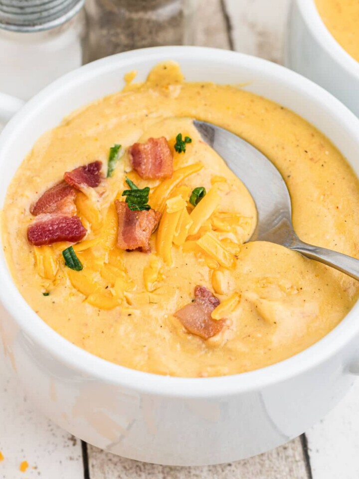 picture of a bowl of saltgrass baked potato soup with bacon and cheese on top with a spoon digging in