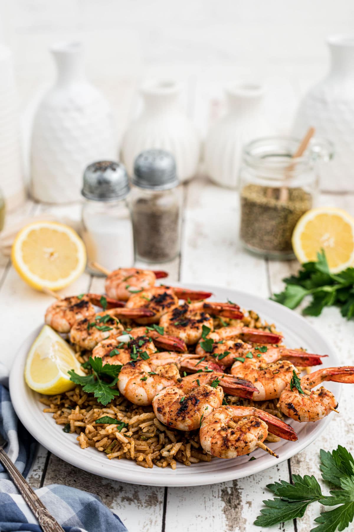 texas roadhouse grilled shrimp skewers on top of seasoned rice with lemons in the background