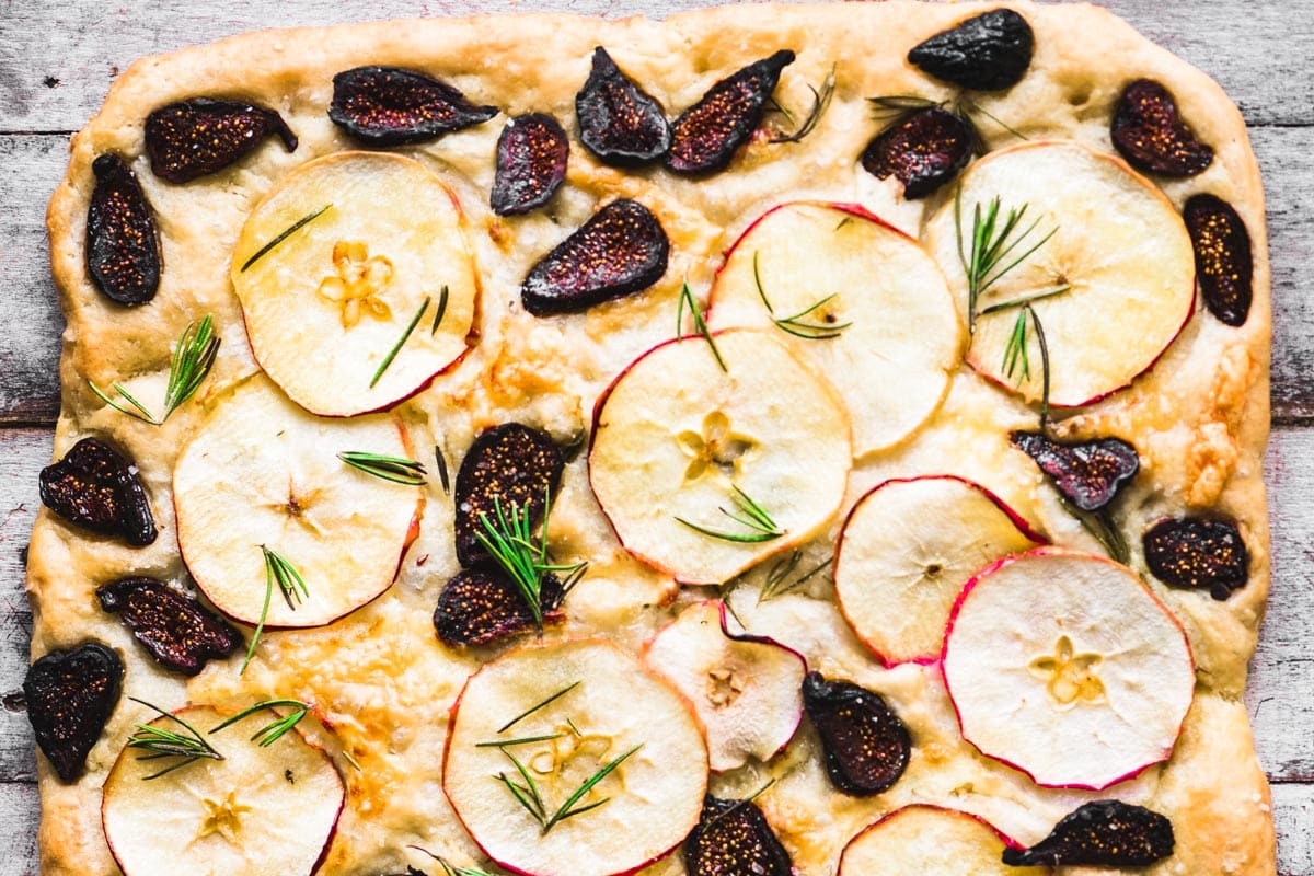 a focaccia bread with slices of apples and figs on top