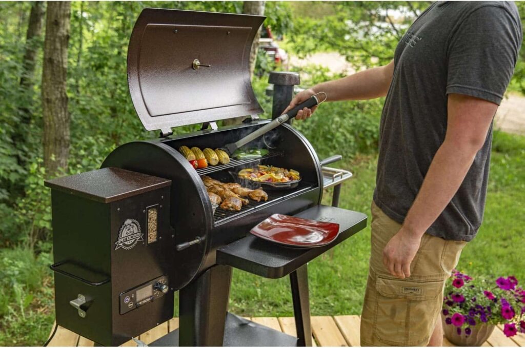 man standing next to a grill flipping meat.