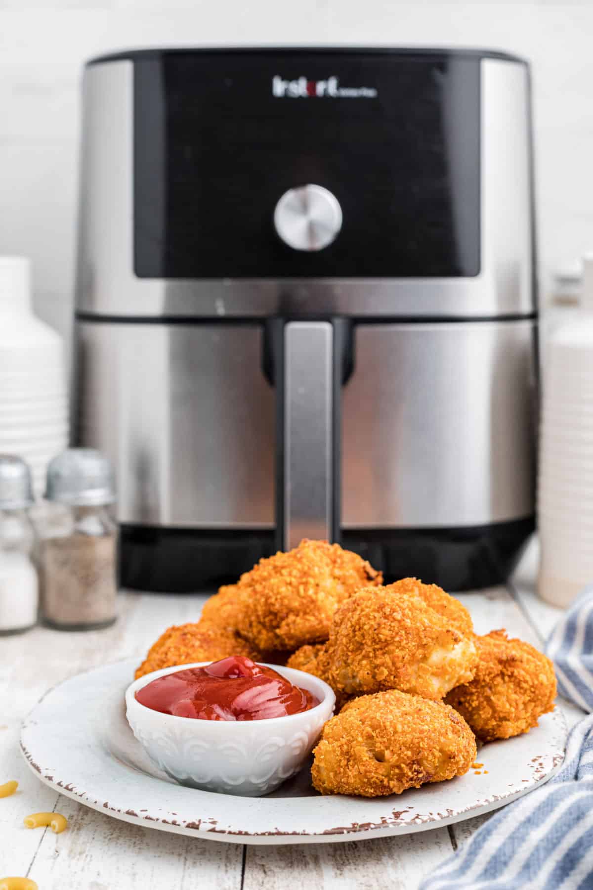 A plate full of mac and cheese bites with an air fryer in the background.