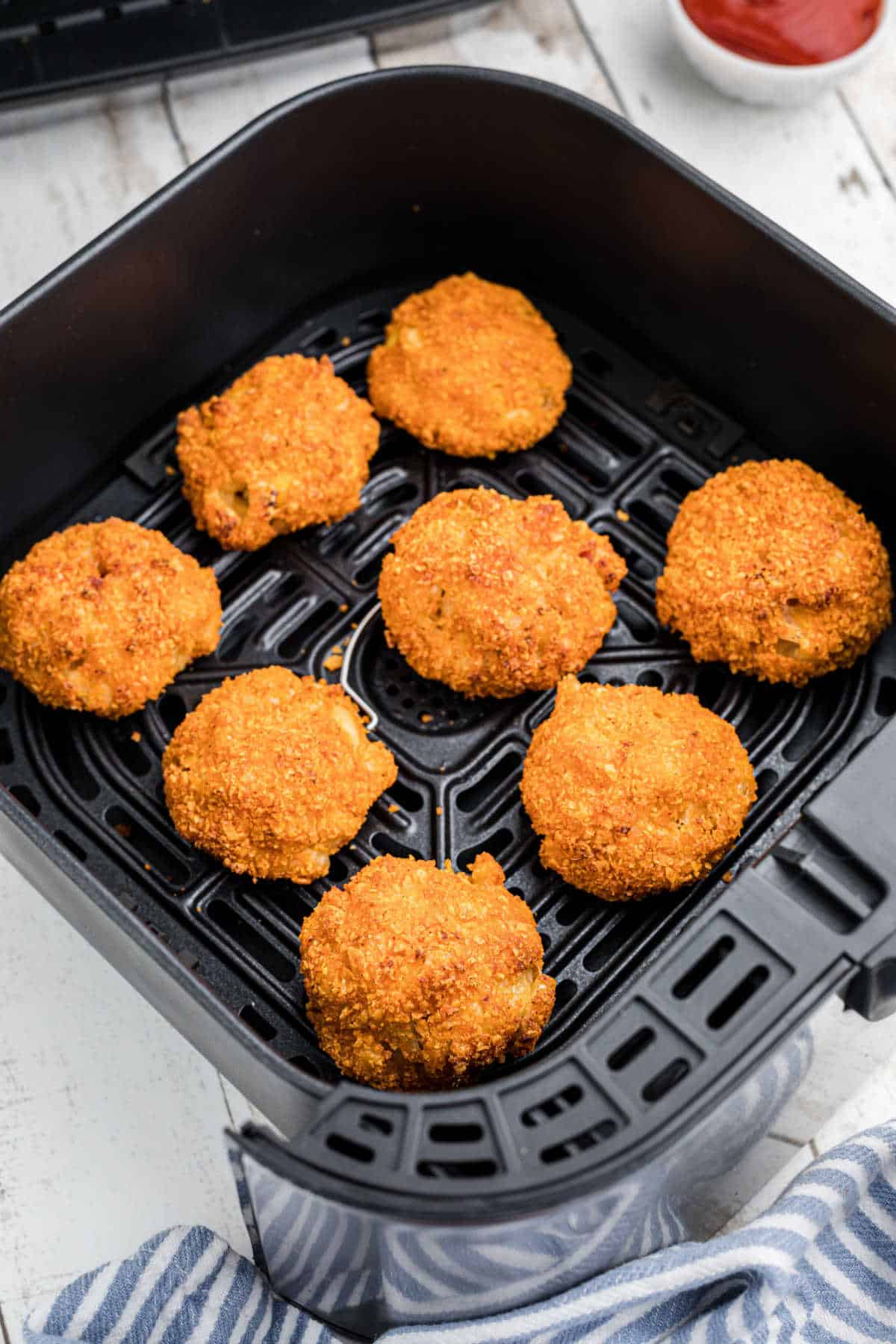 An air fryer basket filled with mac and cheese bites.
