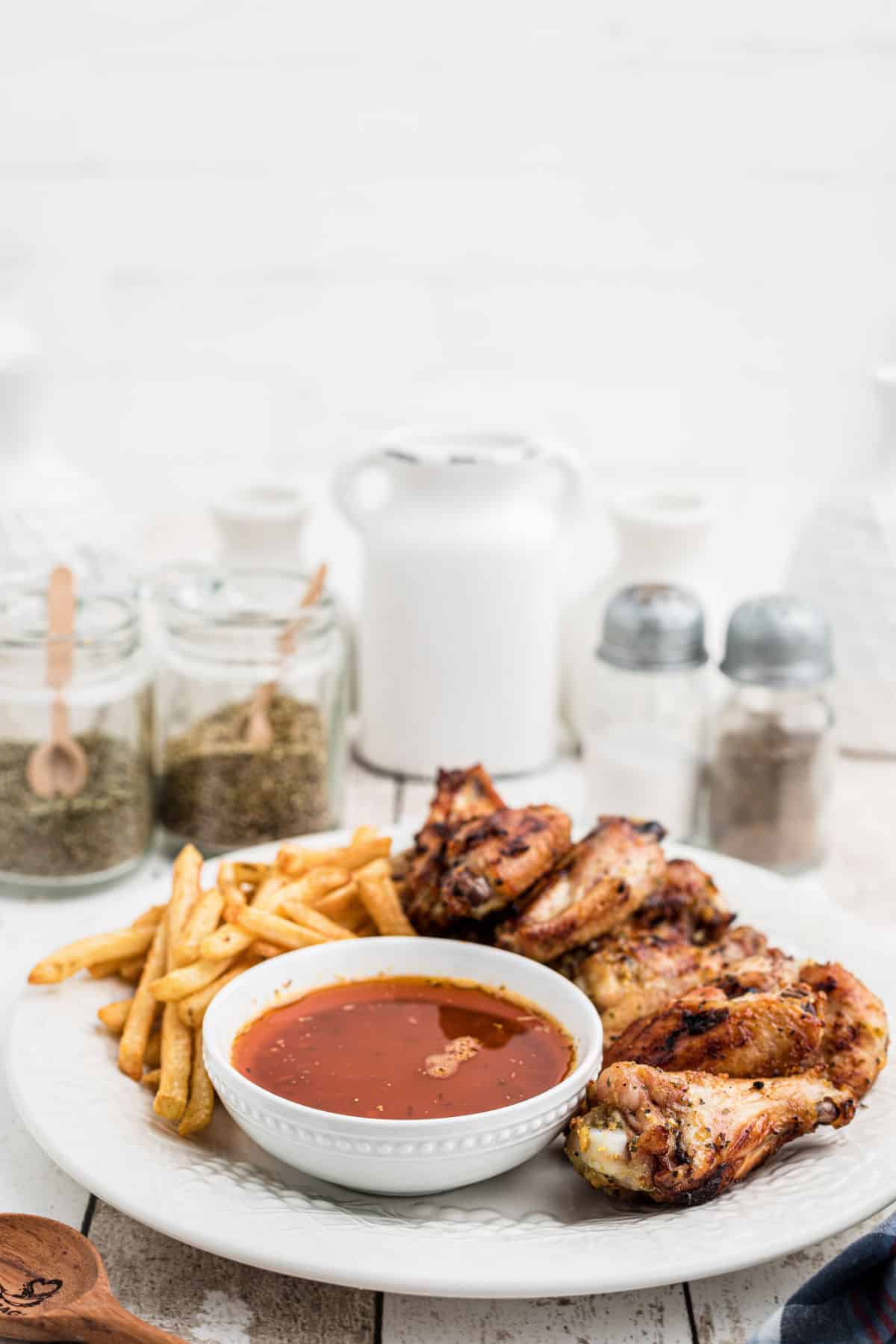 side view of a plate of chicken wings with french fries and cajun butter sauce.