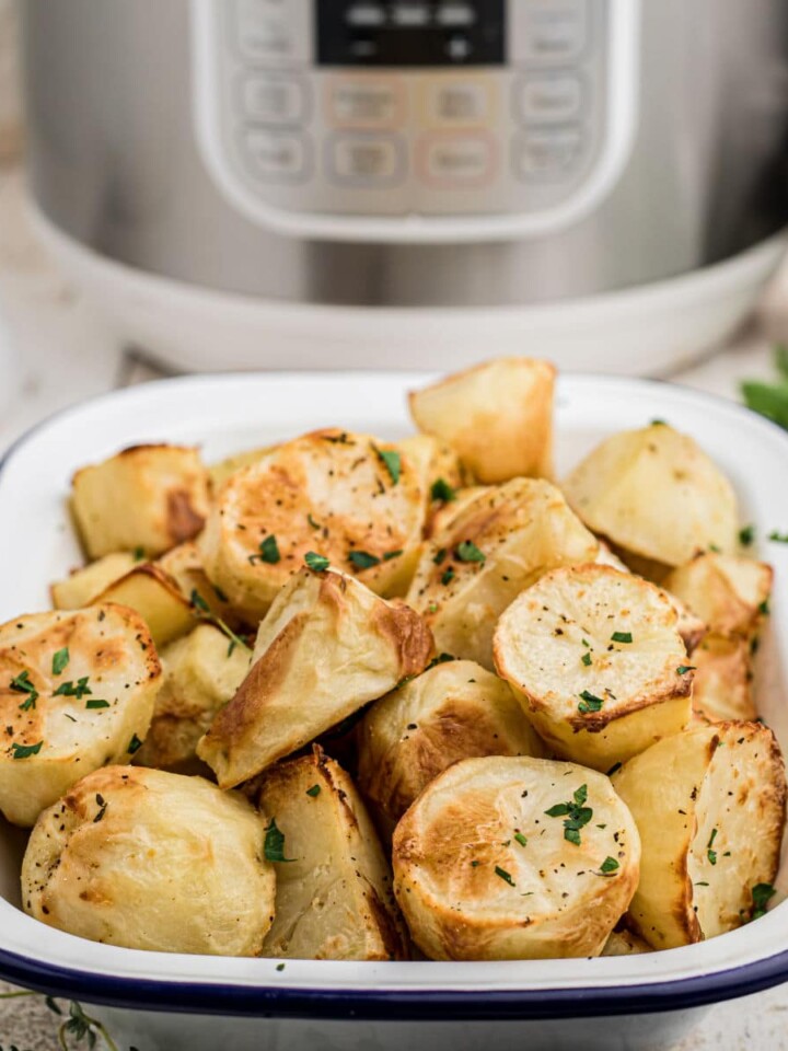 a dish full of crispy potatoes in front of an instant pot