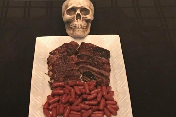 a dish full of ribs and sausages with a skull on top