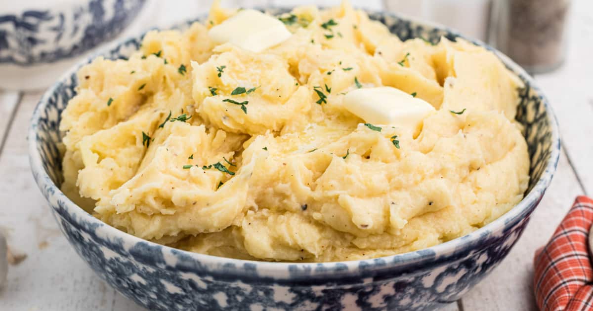 close up of a big bowl of mashed potatoes with some butter melting on top.