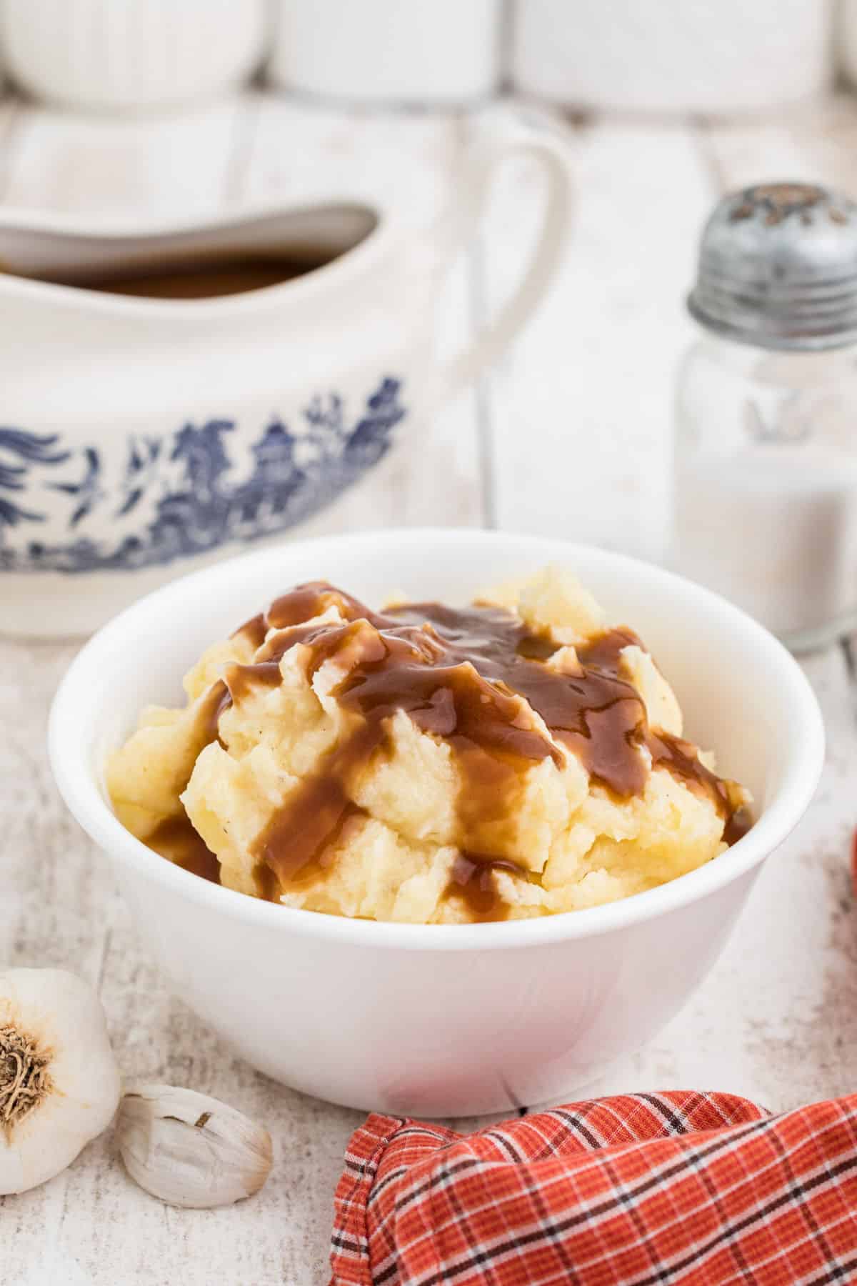 A bowl of mashed potatoes with gravy poured on top.
