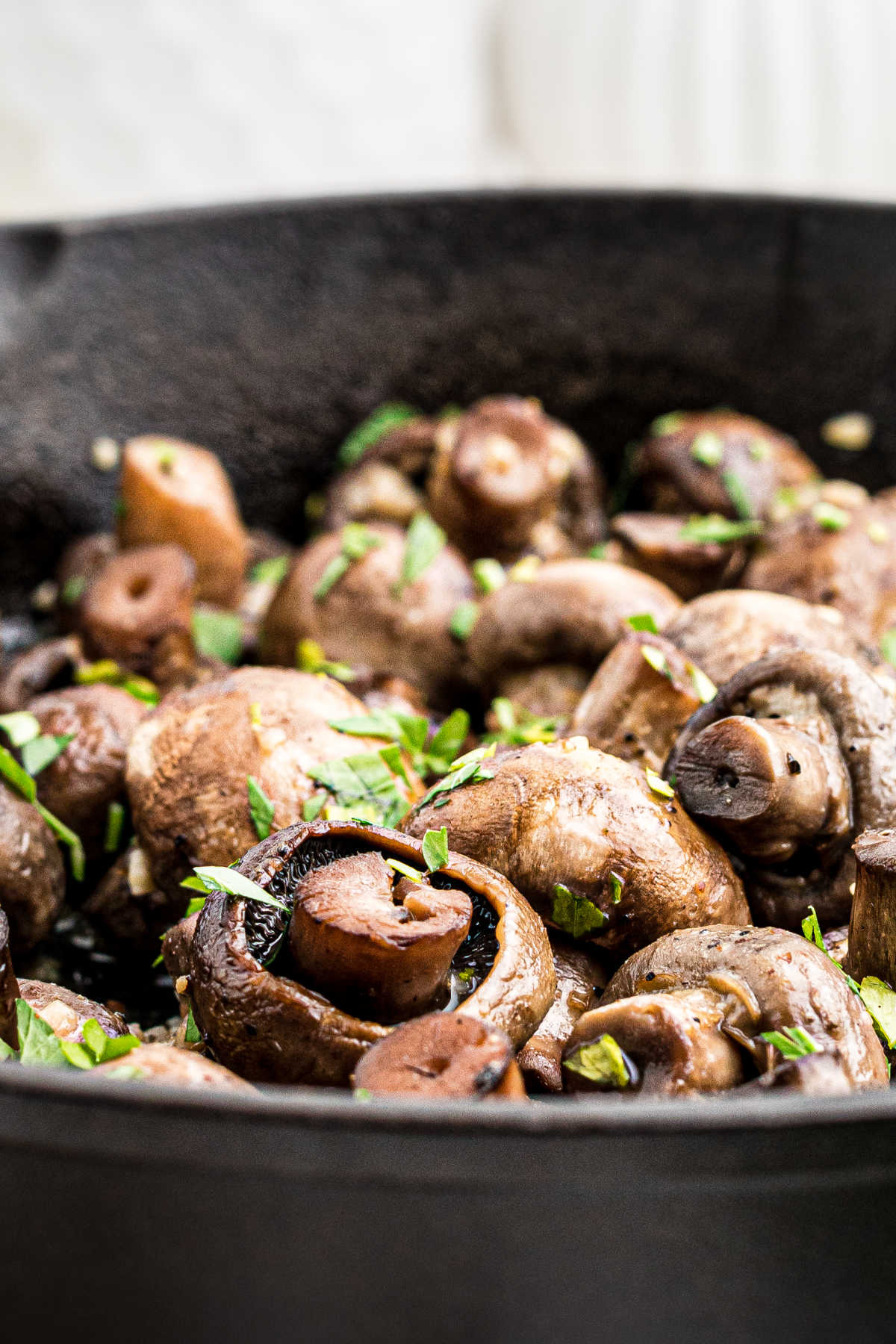 close up from the side of some smoked mushrooms in a cast iron pot.