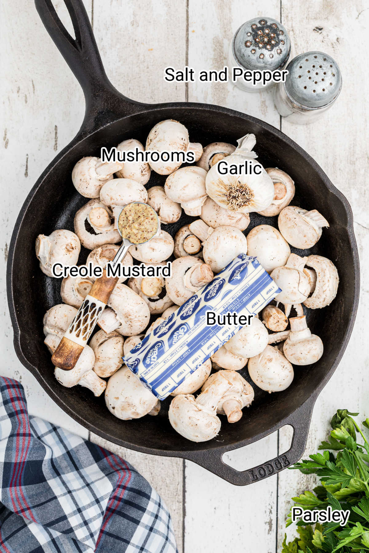overhead shot of a cast iron pot full of mushrooms with a stick of butter and some garlic.