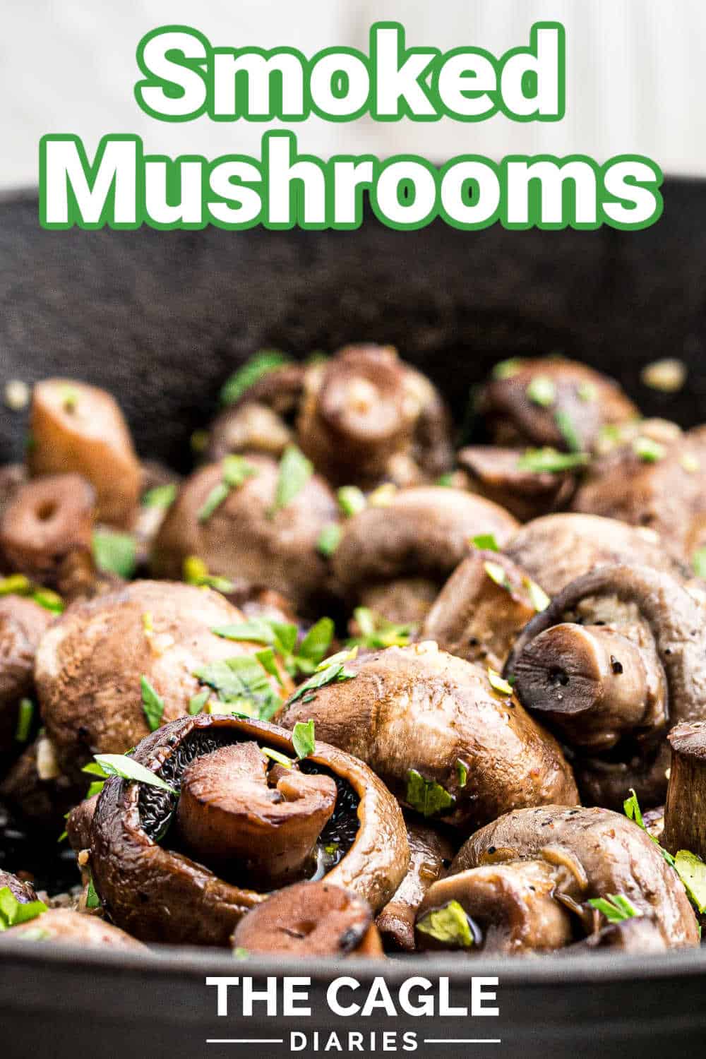 close up of a cast iron pan full of smoked mushrooms sprinkled with parsley with a pinterest