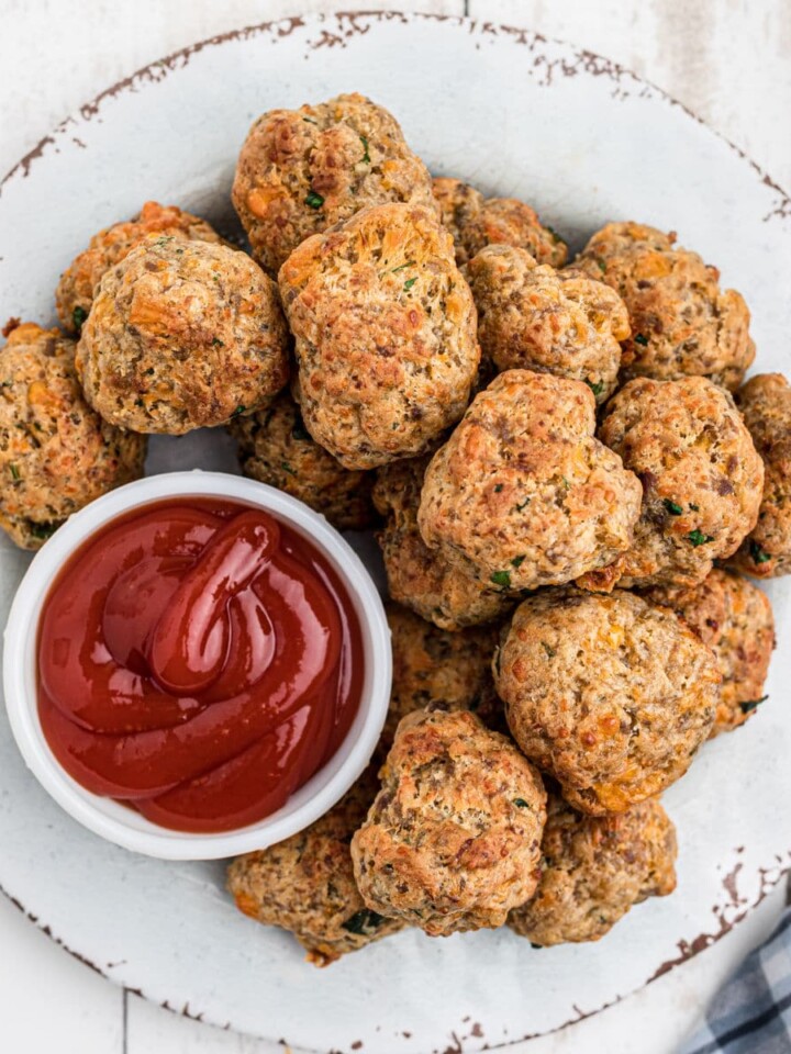 Close up overhead shot of air fryer sausage balls on a plate with ketchup.