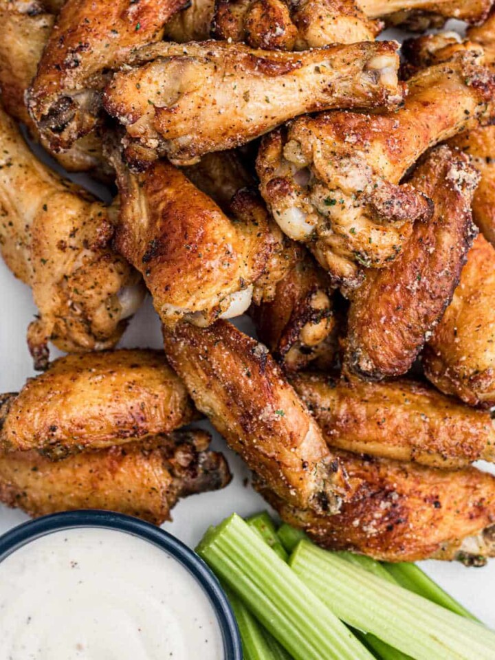 A close up shot of some air fried ranch chicken wings with some celery and ranch dip.