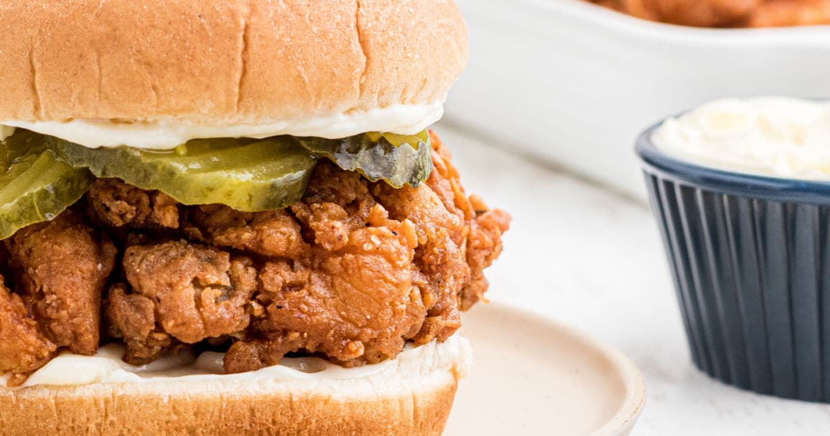 close up side view of a fried chicken sandwich.