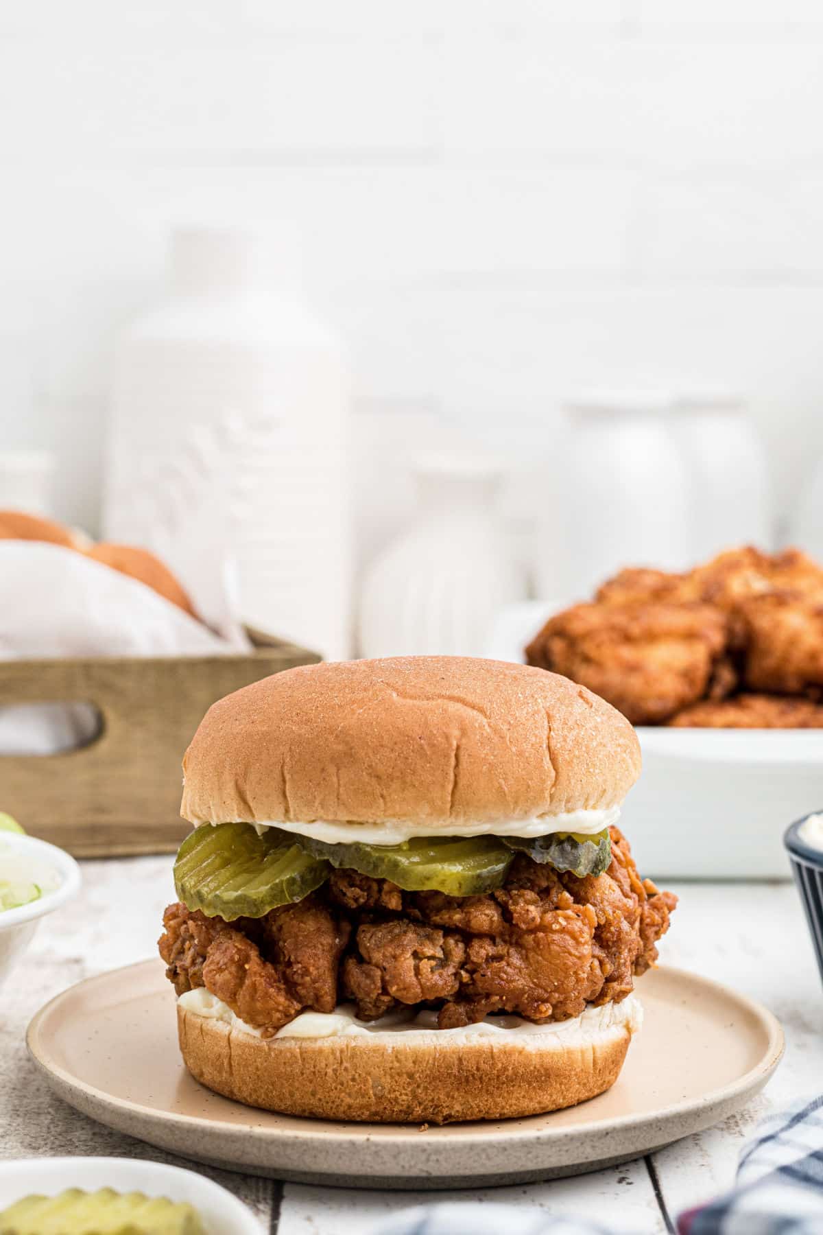 A straight on shot of a fried chicken sandwich, with pickles on it.