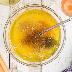 Overhead shot of a bowl of butter with seasonings and a whisk about to stir.