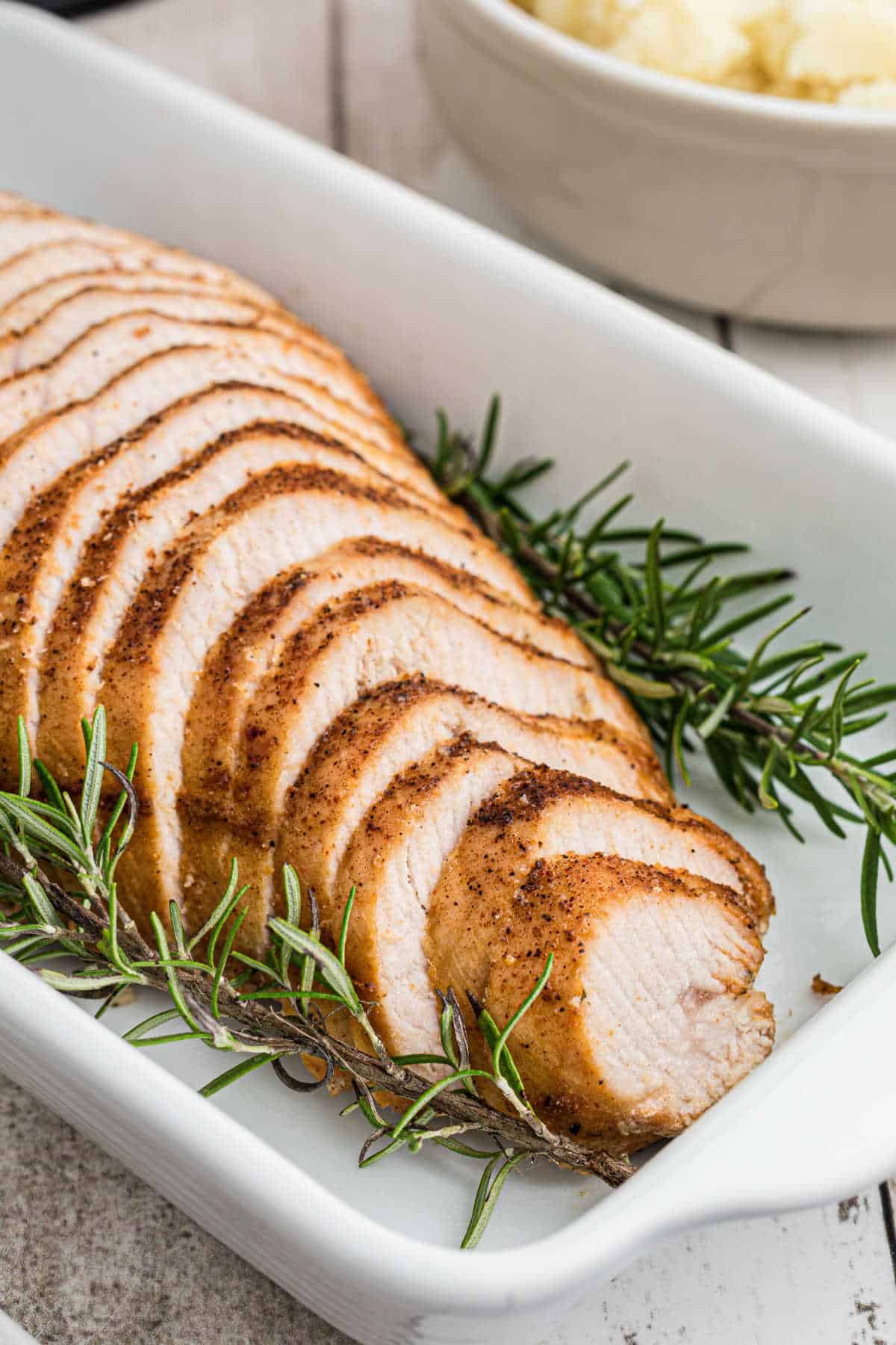 A turkey breast sliced and looking pretty in a baking dish.