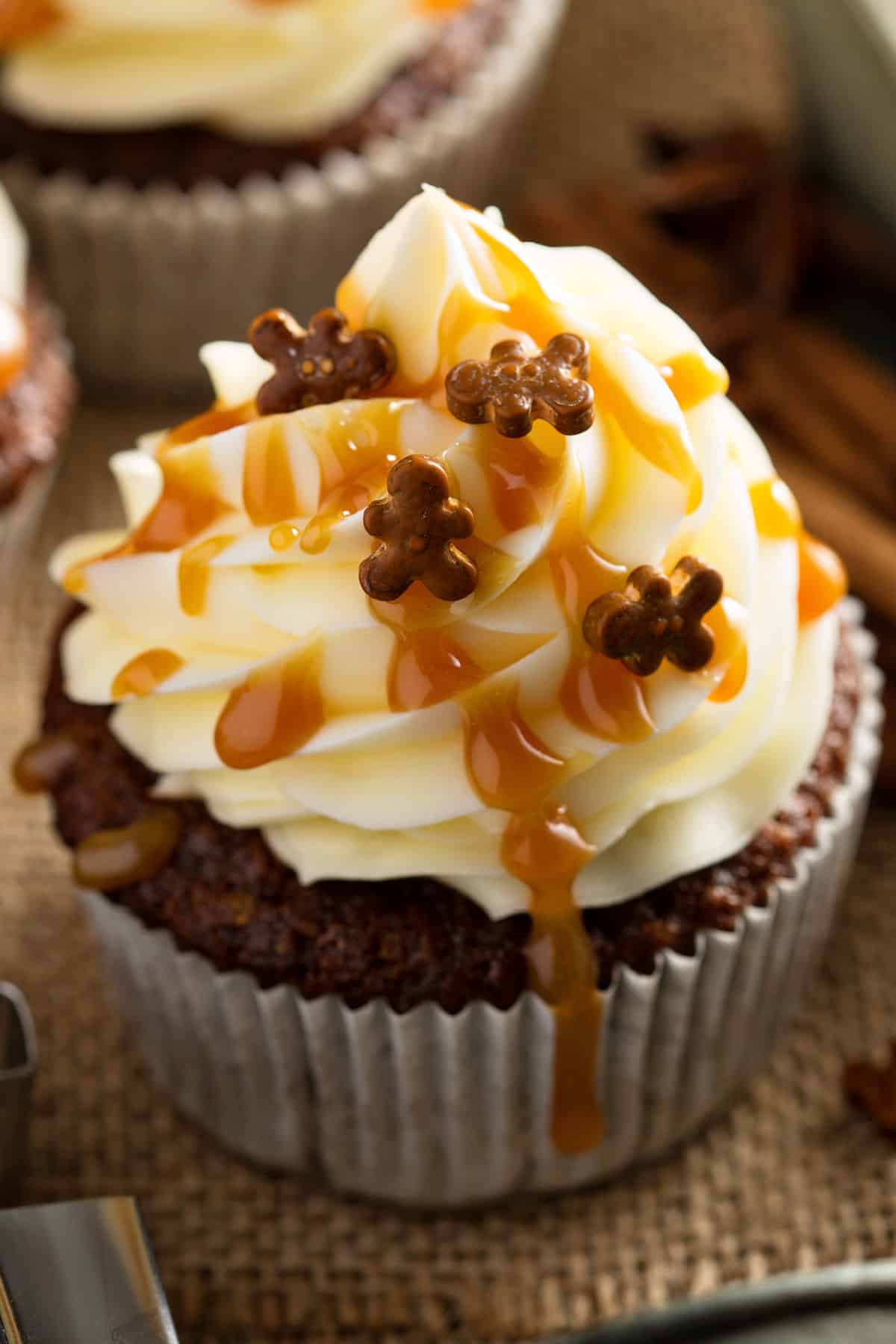 A gingerbread cupcake with cream cheese frosting on top with gingerbread sprinkles.
